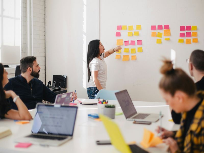 A team leader coaching colleagues during a hands-on training session at a whiteboard